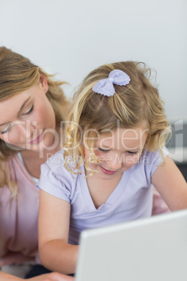 Girl using laptop with mother