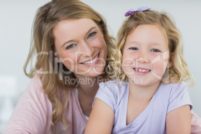 Girl and mother smiling together at home