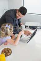 Businessman pointing at laptop while looking at daughter