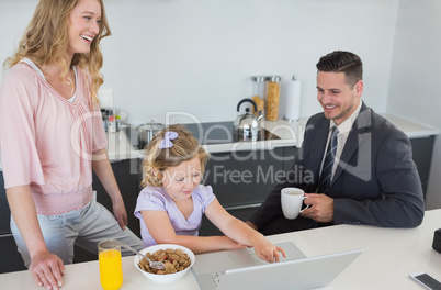 Parents with daughter using laptop during breakfast time