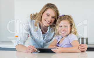 Mother and daughter holding digital tablet at table