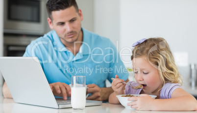 Father looking at daughter having breakfast