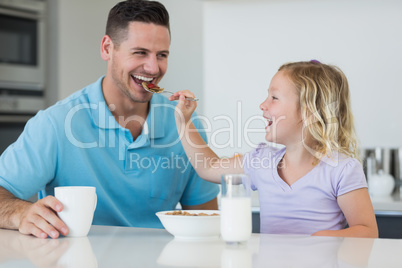 Daughter feeding cereals to father at table