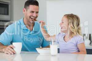 Daughter feeding cereals to father at table