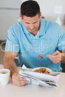 Man reading newspaper while eating breakfast