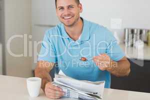 Man with newspaper having cereals at table