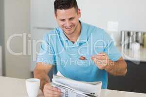 Man reading newspaper while having breakfast at table