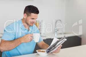Man reading newspaper while drinking coffee