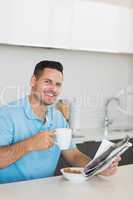 Man with newspaper drinking coffee at table