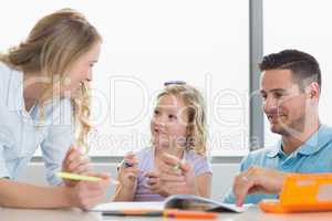 Parents assisting girl in drawing at table