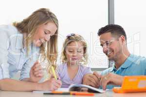 Parents assisting daughter in drawing at table