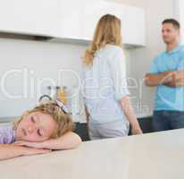Girl leaning on table while parents arguing