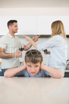 Boy covering ears while parents arguing
