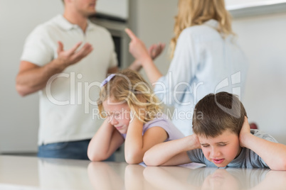 Children covering ears while parents arguing