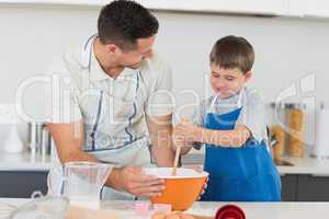 Father and son making cookies at counter