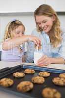 Mother with daughter dipping cookie in milk