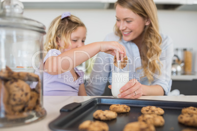 Woman with daughter dipping cookie in milk