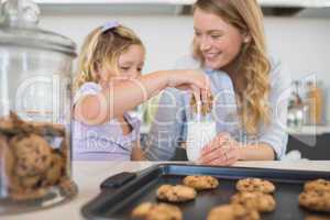 Woman with daughter dipping cookie in milk