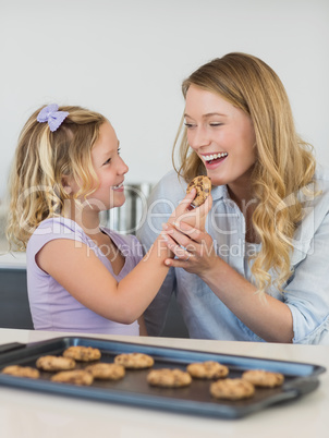 Girl feeding cookie to mother