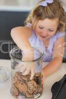 Girl reaching for cookies in jar