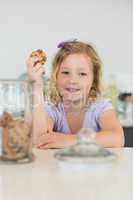 Cute girl holding cookie at counter