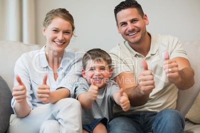 Family gesturing thumbs up on sofa