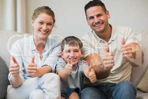 Family gesturing thumbs up on sofa