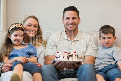 Family with cake sitting on sofa