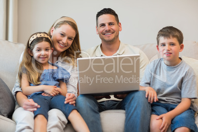 Happy family with laptop on sofa