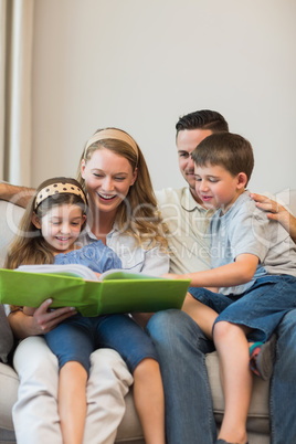 Family watching photo album on sofa at home