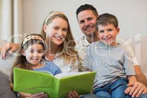 Family with photo album sitting on sofa