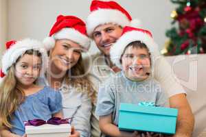 Family wearing Christmas hat while holding presents