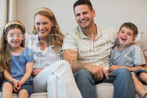Happy parents and children sitting on sofa