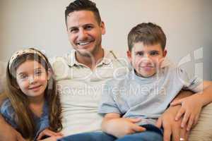 Father and children smiling on sofa