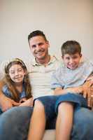 Father with son and daughter smiling on sofa