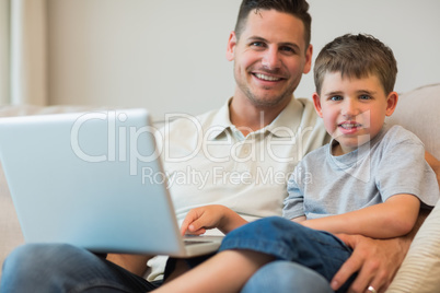 Father and boy with laptop on sofa