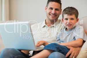 Father and boy with laptop on sofa