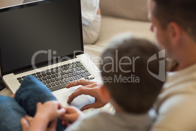 Father and son using laptop in house
