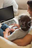 Father teaching boy in using laptop