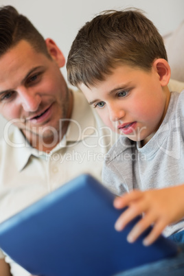 Boy using digital tablet with father