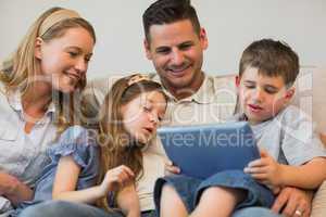 Family using digital tablet together on sofa