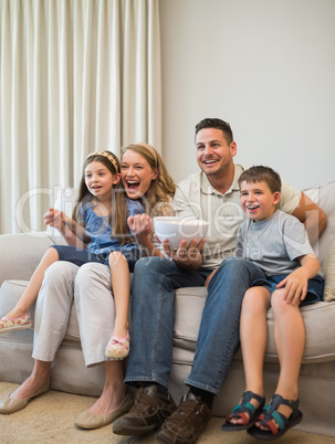 Excited family watching television on sofa