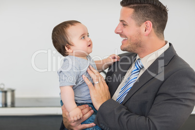 Businessman looking at baby boy in kitchen