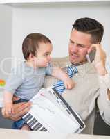 Businessman carrying baby and documents while on call