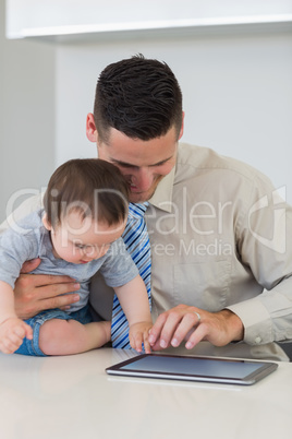 Businessman and baby boy using digital tablet