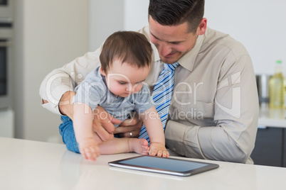 Businessman holding baby using tablet computer
