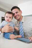 Businessman with digital tablet holding baby