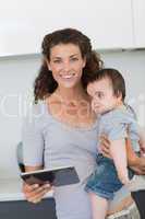 Happy mother with digital tablet carrying baby