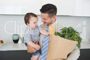 Businessman carrying baby and groceries