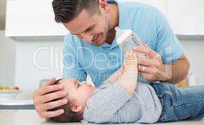 Caring father feeding milk to baby